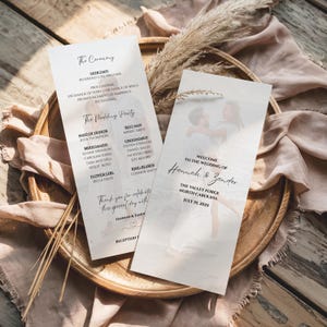 Peut inclure: Deux programmes de cérémonie de mariage sur un plateau en bois. Les programmes présentent les noms des mariés et les détails de la cérémonie. Un programme comporte une photo d'un couple. La date du mariage est le 19 juillet 2025.