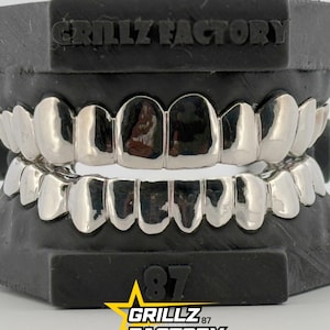 Full set silver custom grillz mounted on a black dental mold display.