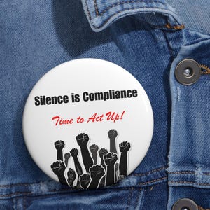 May include: A white button with black text that reads "Silence is Compliance Time to Act Up!" and a graphic of raised fists.