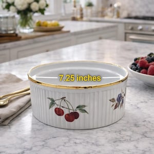 Może przedstawiać: Białe ceramiczne naczynie do pieczenia ze złotą obwódką i wzorem wiśni. Naczynie ma średnicę 18,4 cm. Naczynie ma żebrowaną fakturę i nadaje się do pieczenia i serwowania.