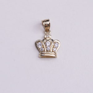 May include: A gold crown pendant with clear cubic zirconia stones.