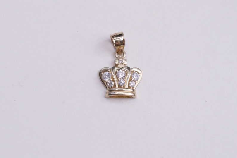 May include: A gold crown pendant with clear cubic zirconia stones.