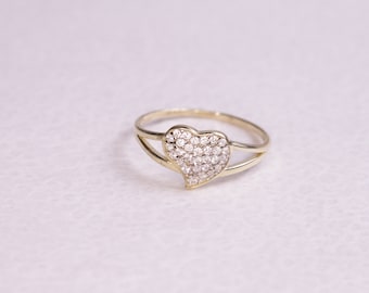 May include: A gold ring with a heart-shaped center set with small, clear stones.