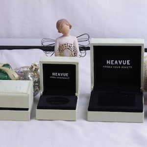 May include: Three white ring boxes with black velvet interiors. The boxes are labeled "Heavue Adorn Your Beauty".