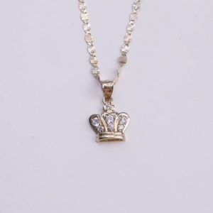 May include: A gold chain necklace with a small crown pendant featuring clear cubic zirconia stones.
