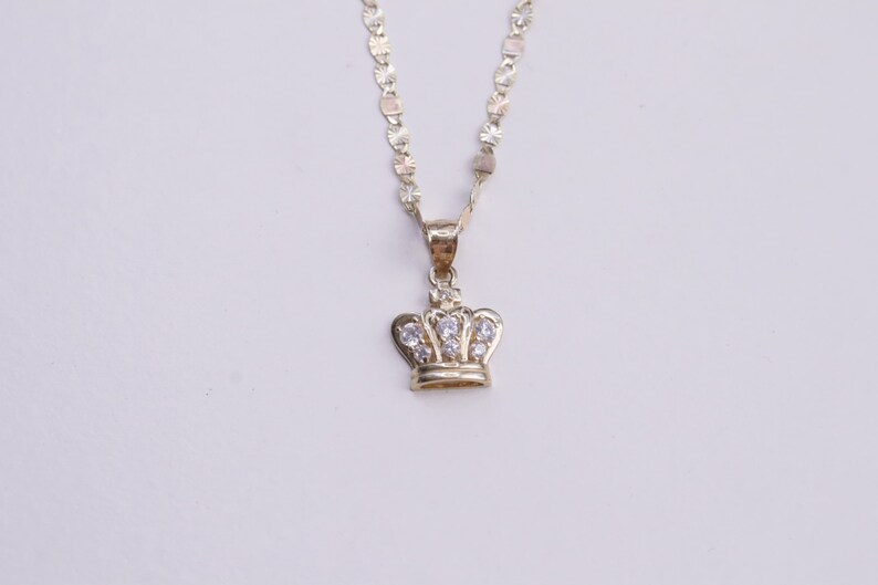 May include: A gold chain necklace with a small crown pendant featuring clear cubic zirconia stones.