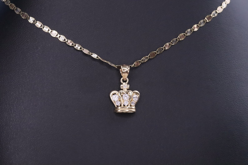 May include: A gold chain necklace with a small crown pendant featuring clear cubic zirconia stones.