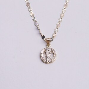 May include: A gold chain necklace with a round pendant featuring a religious figure and clear stones.