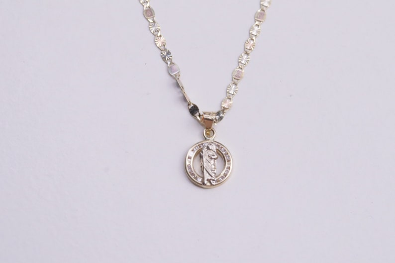 May include: A gold chain necklace with a round pendant featuring a religious figure and clear stones.