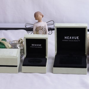 May include: Three white ring boxes with black velvet interiors. The boxes are labeled "Heavue Adorn Your Beauty".