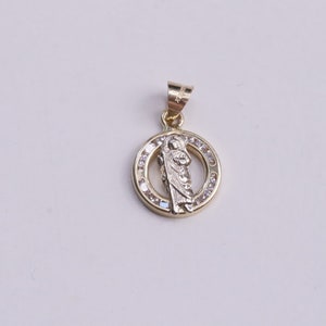 May include: A gold pendant with a religious figure in the center surrounded by clear stones.
