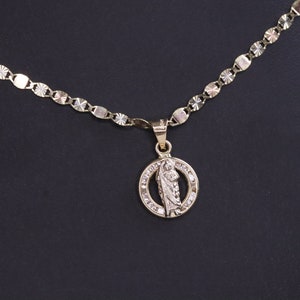 May include: A gold chain necklace with a pendant featuring a religious figure in a circle with small clear stones around the edge.