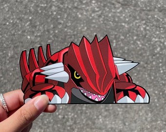 May include: A red and black cartoon monster with sharp teeth and yellow eyes. The monster is peeking out from behind a white surface.