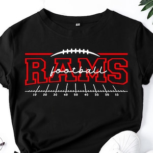 May include: A black short-sleeve t-shirt featuring a red graphic with the text RAMS and football in white script. The design includes a white football icon and a field yard line graphic with numbers 10, 20, 30, 40, 50, 40, 30, 20, 10.