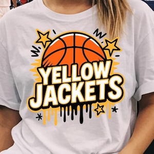 May include: White t-shirt with a basketball graphic and the text "YELLOW JACKETS". The design features an orange basketball, yellow stars, and dripping paint effect. The shirt is paired with denim shorts.