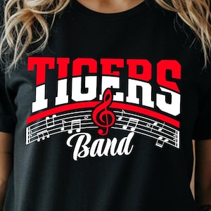 May include: Black t-shirt with the words "TIGERS Band" in red and white lettering. A musical treble clef and musical notes are featured below the word "TIGERS". The shirt has short sleeves.