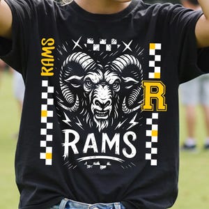 May include: Black t-shirt with a white and black graphic of a ram's head, the word "RAMS" in white, and the letter "R" in yellow. The shirt has a checkered pattern and the word "RAMS" vertically on the left side.