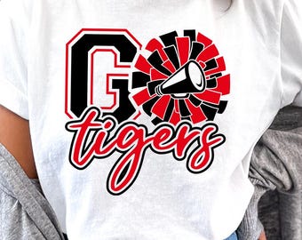 May include: White t-shirt with a graphic that says "GO tigers" in black and red. The "G" is outlined in black with a red border. A cheerleader's pom-pom and megaphone are also featured in the design.