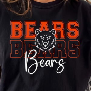 May include: Black t-shirt with the word "BEARS" in orange block letters, repeated three times. A white bear head graphic is centered above the word "Bears" in a cursive font. The shirt has short sleeves and a crew neck.