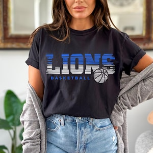 May include: Black t-shirt with a graphic of the word "LIONS" in white with blue stripes and a basketball graphic. The text "BASKETBALL" is below the graphic.