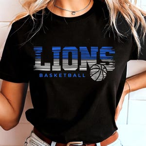 May include: Black t-shirt with a blue and white graphic that says "LIONS BASKETBALL" with a basketball graphic.