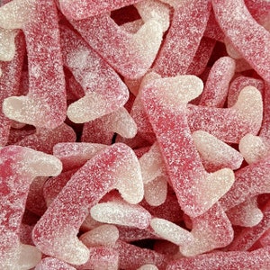 May include: A close-up of pink and white gummy sweets shaped like a foot. The sweets are covered in a fine sugar coating.