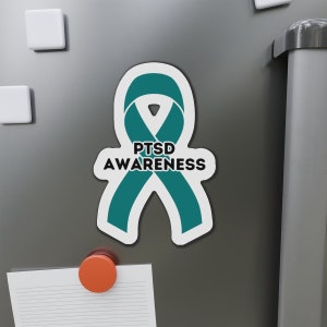 Könnte beinhalten: Türkisfarbenes Band mit dem Text "PTSD AWARENESS" in schwarzen Buchstaben. Das Band befindet sich auf einem weißen Hintergrund.