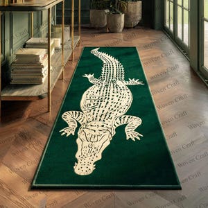 May include: A green rectangular rug with a large white alligator motif. The rug is placed in a hallway with wooden flooring. The rug's design is a striking feature, adding a unique touch to the space. The rug is a decorative item.