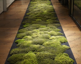 Puede incluir: Una alfombra rectangular larga con un fondo oscuro está cubierta por una densa capa de musgo verde vibrante. La alfombra recorre un pasillo con pisos de madera y paredes blancas. Las palabras "Woven Craft" están impresas en el lateral de la alfombra.