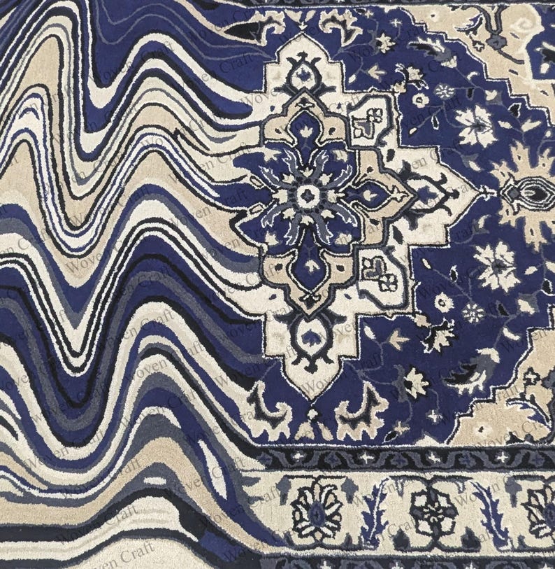 May include: A detailed close-up of a rug with a unique design. The rug features a blend of blue, beige, and white colors. The left side has a wavy pattern, while the right side showcases a traditional floral motif. The rug's border has a repeating floral design.