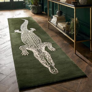Può includere: Un tappeto rettangolare verde con un design di alligatore bianco. Il tappeto è posto su un pavimento in legno. Il tappeto è un elemento decorativo per la casa.