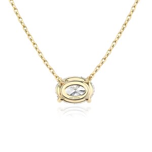May include: A gold chain necklace with a large oval-shaped pendant featuring a clear stone surrounded by smaller clear stones. The pendant is engraved with the text "TINY HOOPS".