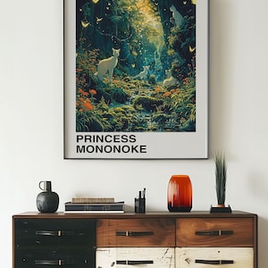 May include: A framed poster with a forest scene featuring a stream, trees, and white animals. The poster is titled "Princess Mononoke" and "Studio Ghibli" in black text. The Japanese text "もののけ姫" is also included.