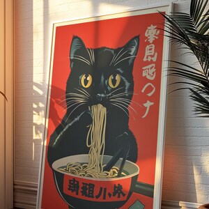 May include: A framed poster featuring a black cat eating ramen from a bowl. The cat is set against a red background with Japanese text. The poster has a white border and is leaning against a white brick wall.