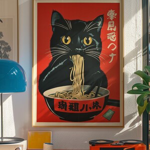 May include: A framed poster featuring a black cat eating ramen from a bowl. The cat has yellow eyes and white whiskers. The background is red with Japanese text. The poster is in a wooden frame.