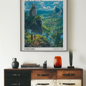 May include: A poster featuring the Studio Ghibli film "My Neighbor Totoro". The poster shows Totoro standing on a cliff overlooking a lush green valley. The text "My Neighbor Totoro" and "Studio Ghibli" are printed in black at the top and bottom of the poster, respectively. The Japanese title "となりのトトロ" is printed in black at the bottom right corner of the poster.