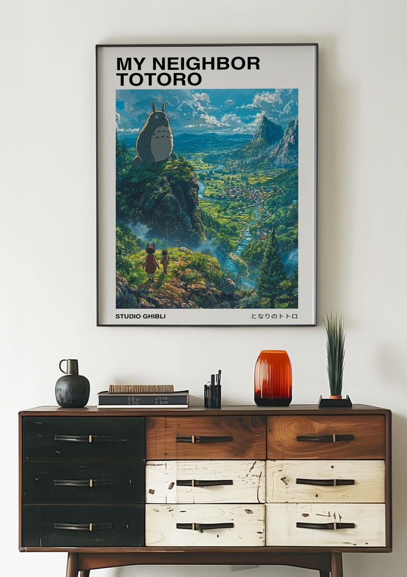 May include: A poster featuring the Studio Ghibli film "My Neighbor Totoro". The poster shows Totoro standing on a cliff overlooking a lush green valley. The text "My Neighbor Totoro" and "Studio Ghibli" are printed in black at the top and bottom of the poster, respectively. The Japanese title "となりのトトロ" is printed in black at the bottom right corner of the poster.