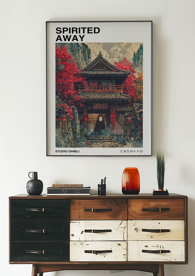 May include: A framed poster with a vintage aesthetic featuring a Japanese-style building with red accents and a character from the animated film Spirited Away. The poster includes the title "Spirited Away", the text "Studio Ghibli", and the Japanese text "となりのトトロ".