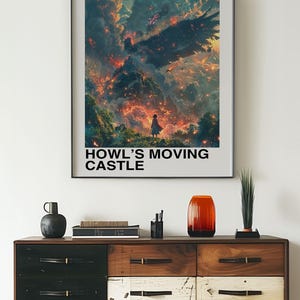 May include: Framed poster featuring artwork from "Howl's Moving Castle." The image depicts a fiery landscape with a figure in the foreground. The poster has the text "HOWL'S MOVING CASTLE" and "STUDIO GHIBLI" at the top. The poster is displayed above a wooden dresser.
