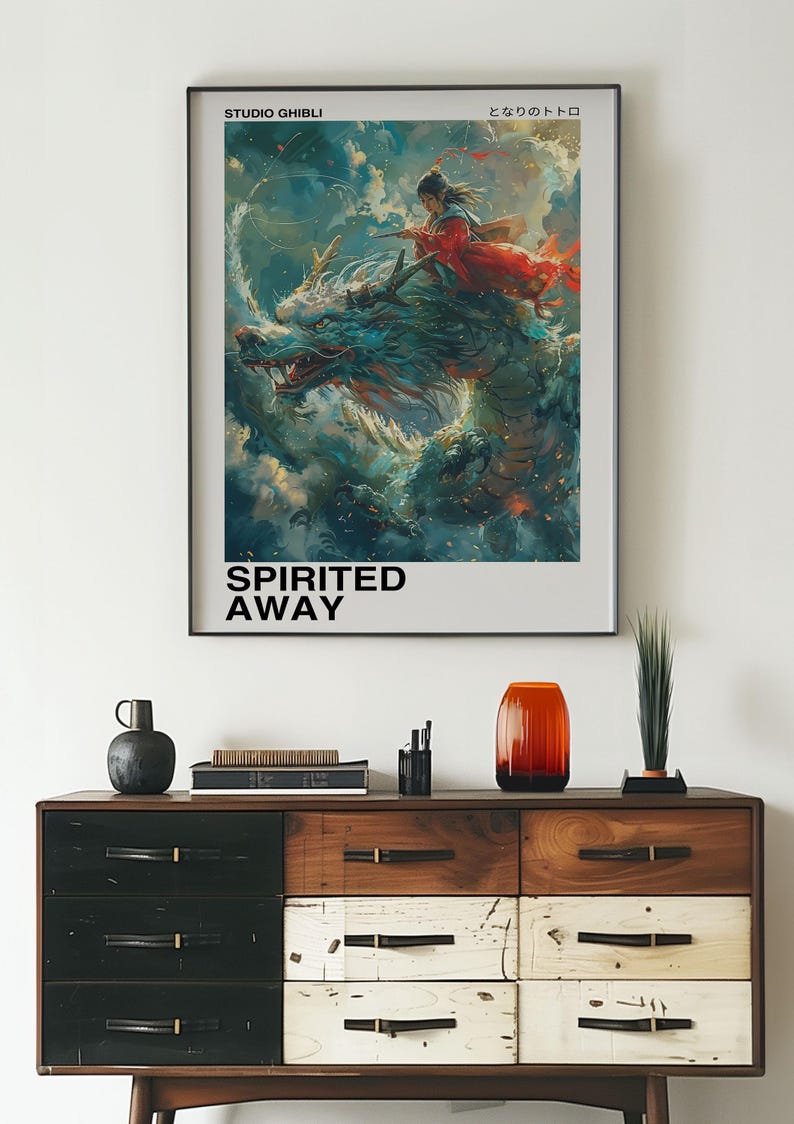 May include: A poster for the Studio Ghibli film "Spirited Away" featuring a young girl riding a dragon in the clouds. The poster has the Japanese text "となりのトトロ" and the title "Spirited Away" in black text.