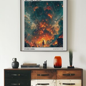 May include: A framed poster featuring the text "HOWL'S MOVING CASTLE" above a vibrant illustration of a fiery castle scene. The poster includes the text "STUDIO GHIBLI" and Japanese text. The poster is displayed above a wooden dresser.