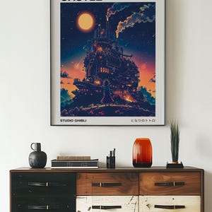 May include: A framed poster featuring the animated film "Howl's Moving Castle." The artwork depicts the castle against a night sky with a large moon. The poster includes the text "HOWL'S MOVING CASTLE" and "STUDIO GHIBLI."