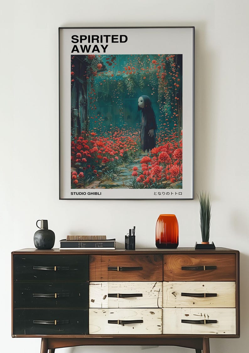 May include: A black framed poster with the title "Spirited Away" in white text. The poster features a still from the animated film, depicting a young girl with a white mask standing in a field of red flowers. The poster also includes the text "Studio Ghibli" and "となりのトトロ" in Japanese.