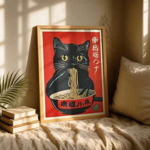 May include: A framed art print featuring a black cat eating ramen from a bowl. The cat has yellow eyes and is set against a red background. Japanese text is visible on the print. The print is in a wooden frame.