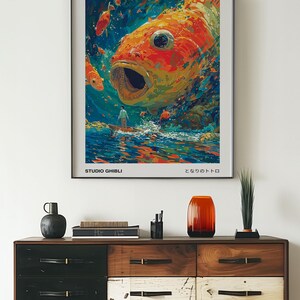 May include: A poster for the Studio Ghibli film "Ponyo" by Hayao Miyazaki. The poster features a large, orange and yellow fish with its mouth open, surrounded by smaller fish. The text "Ponyo" is in black letters at the top of the poster, and the text "Studio Ghibli" is in black letters at the bottom of the poster. The text "となりのトトロ" is in Japanese at the bottom of the poster.