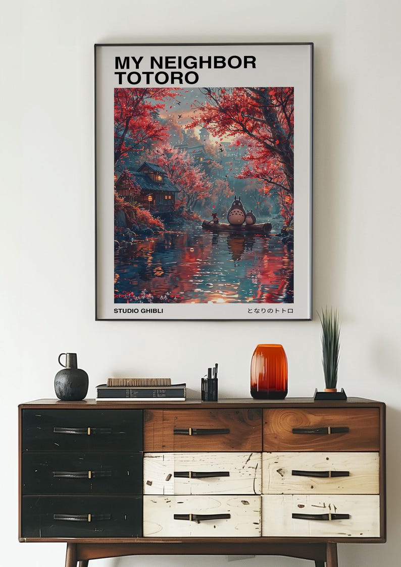 May include: A poster featuring a whimsical illustration of Totoro, a beloved character from the Studio Ghibli film "My Neighbor Totoro". The poster depicts Totoro sitting on a boat in a serene forest setting with a small house and a river in the background. The poster has the title "My Neighbor Totoro" and the text "Studio Ghibli" and "となりのトトロ" in Japanese.