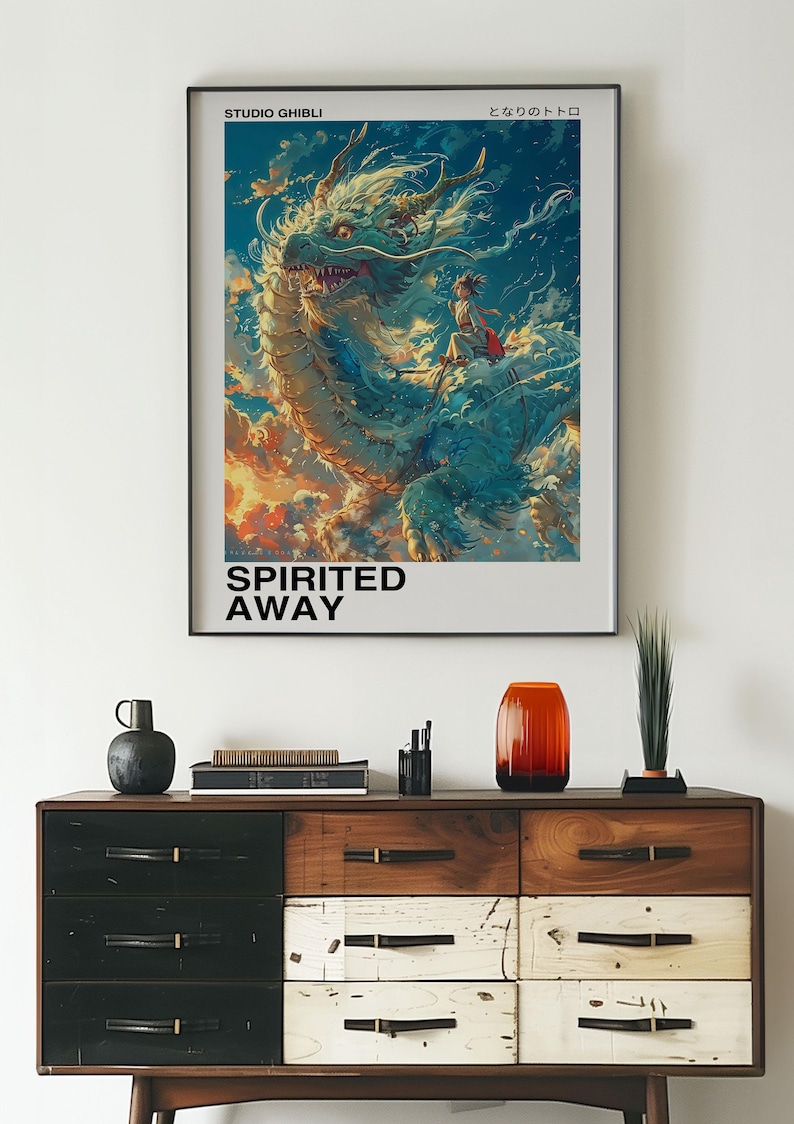 May include: A poster for the Studio Ghibli film Spirited Away, featuring a white dragon with a young girl riding on its back. The poster has the Japanese text "となりのトトロ" and the English text "Spirited Away" on it.