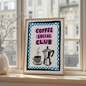 Könnte beinhalten: Gerahmter Kunstdruck mit den Worten "COFFEE SOCIAL CLUB" in Rosa und Schwarz. Der Druck zeigt eine Kaffeetasse, eine Untertasse und einen Espressokocher. Der Rand ist blau und weiß kariert.
