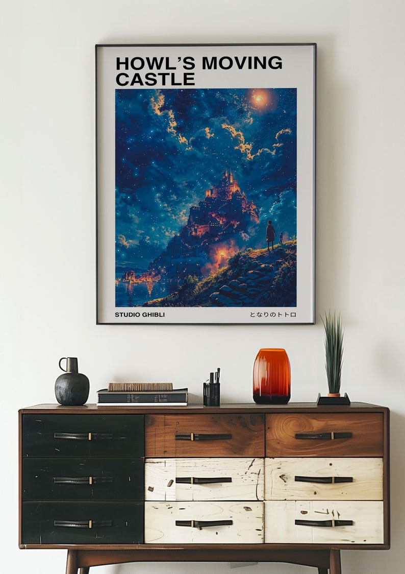 May include: A framed poster featuring the artwork from Howl's Moving Castle, with the text "HOWL'S MOVING CASTLE" at the top. The image depicts a castle on a hill under a starry sky. The words "STUDIO GHIBLI" are at the bottom.