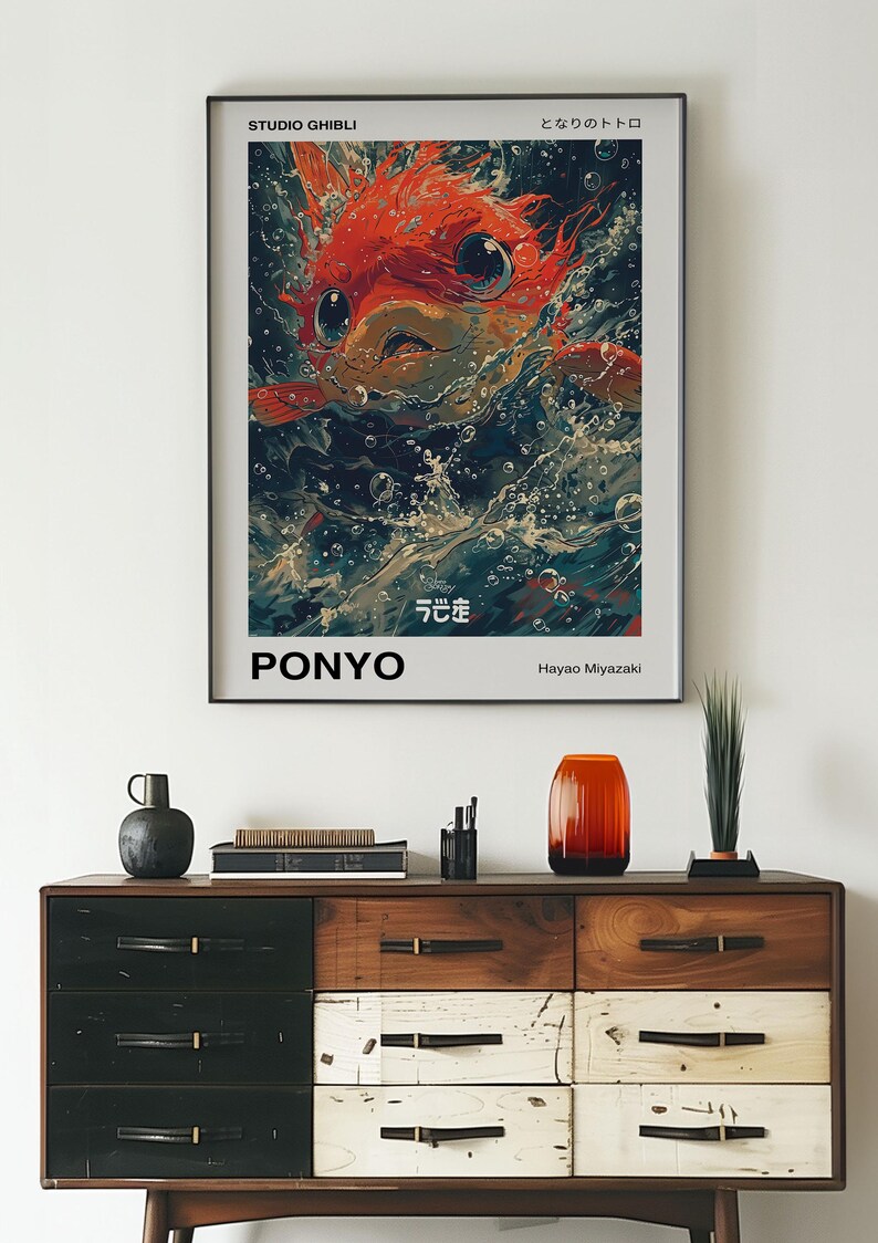 May include: A poster for the Studio Ghibli film "Ponyo" featuring a red fish with large eyes and a white background. The text on the poster reads "Studio Ghibli", "Ponyo", "Hayao Miyazaki", and "となりのトトロ" in Japanese.